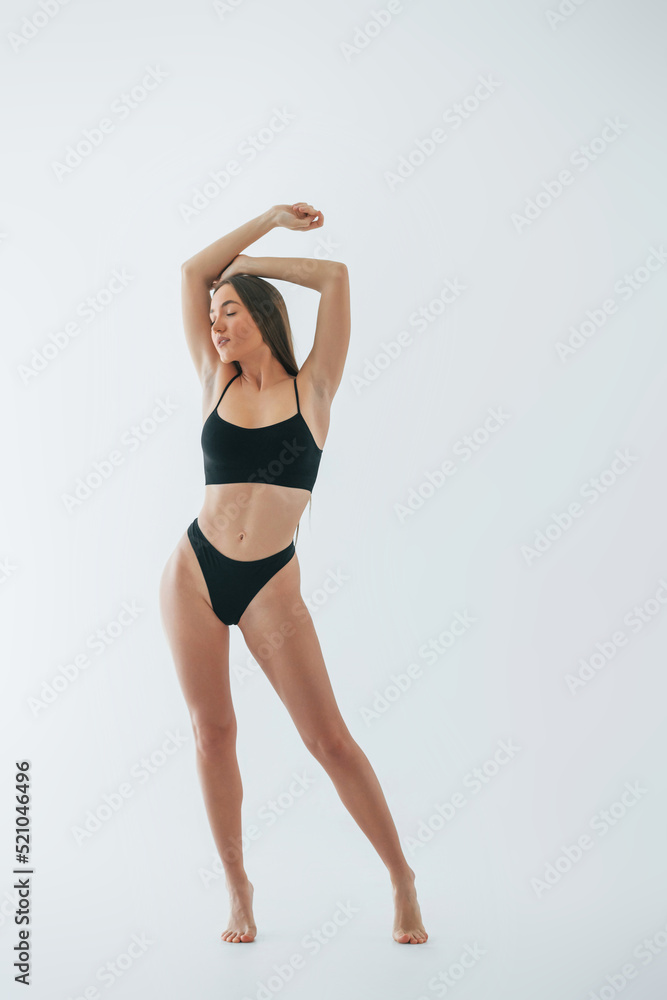 Standing in black lingerie. Woman in underwear with slim body type is posing in the studio Standing in black lingerie. Woman in underwear with slim body type is posing in the studio