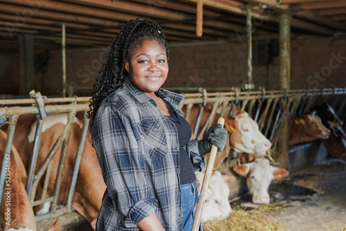 Young african farmer woman looking at camera while working inside cowshed