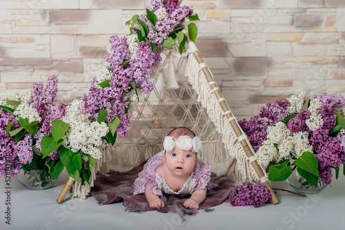 newborn girl in a white wreath near lilac flowers. baby's first photo session. little daughter