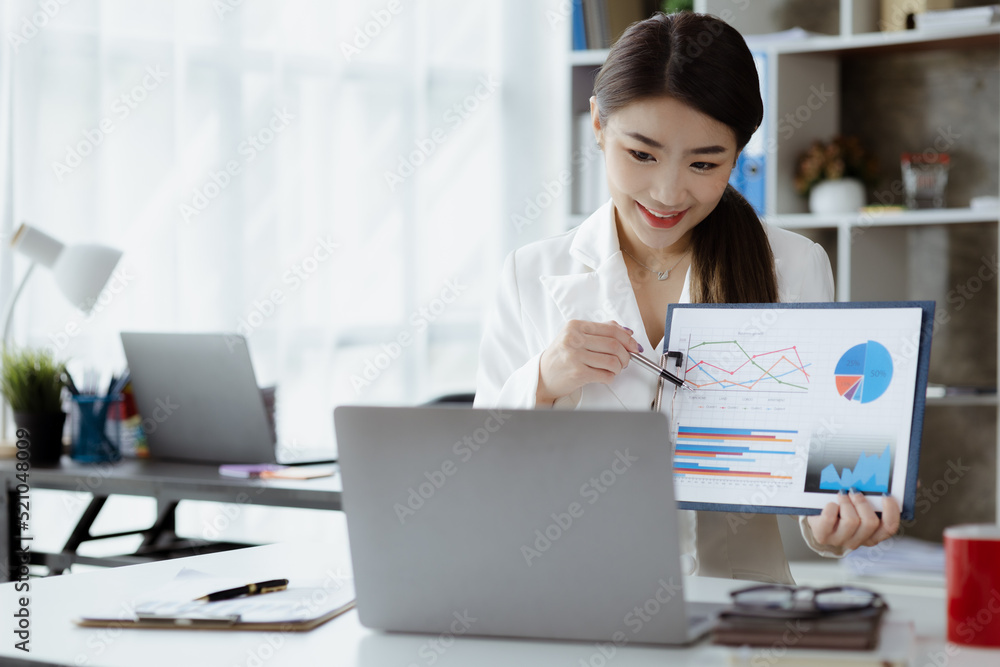 Asian woman working in office and discussing with business partner via laptop video call, young Asian business woman is business executive, founding startup executive. Startup business concept. Asian woman working in office and discussing with business partner via laptop video call, young Asian business woman is business executive, founding startup executive. Startup business concept.