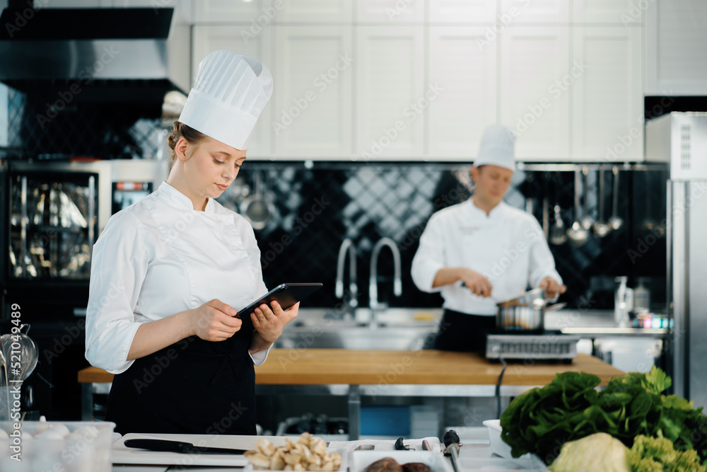 Professional kitchen of a restaurant, a female chef checks the availability of products from an employee. Restaurant warehouse analytics. Preaplist checking