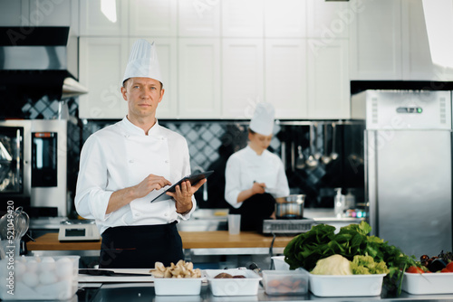 Professional kitchen of a restaurant, a male chef checks the availability of products from an employee. Restaurant warehouse analytics. Preaplist checking