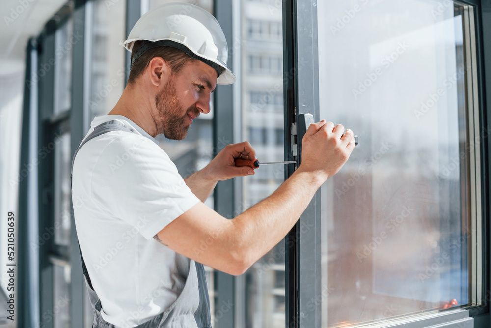 Installing new windows. Close up view of repairman that is working indoors in the modern room Installing new windows. Close up view of repairman that is working indoors in the modern room