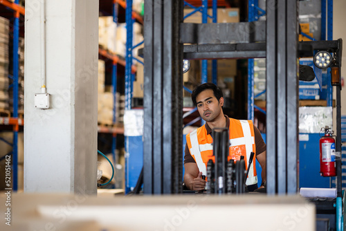 Smart engineer man worker doing stocktaking of product management in forklift machine on shelves in warehouse. Factory physical inventory count.