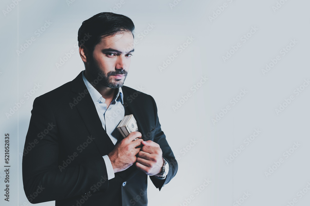 Portrait of Caucasian businessman in suit hides Dollars. Cheerful manager holding dollar banknotes, rejoicing successful profitable deal. man hides or takes wad of money from his pocket. Portrait of Caucasian businessman in suit hides Dollars. Cheerful manager holding dollar banknotes, rejoicing successful profitable deal. man hides or takes wad of money from his pocket.