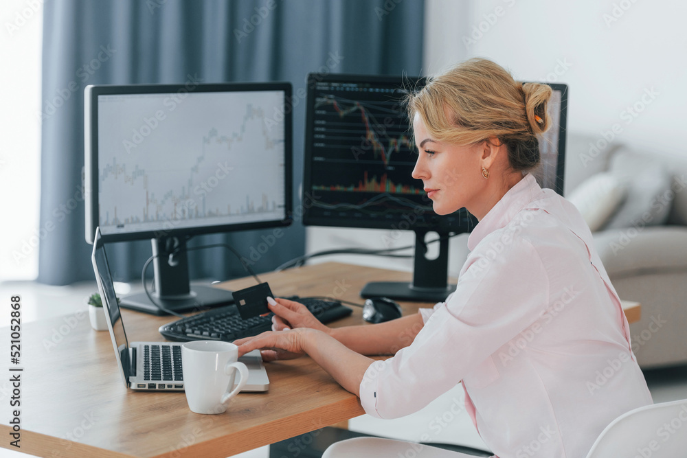 Using credit card for payment. Female stock broker in formal wear is working in the office Using credit card for payment. Female stock broker in formal wear is working in the office