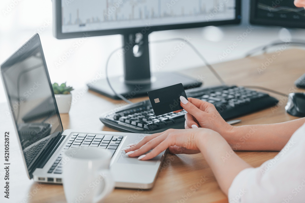 Using credit card for payment. Female stock broker in formal wear is working in the office Using credit card for payment. Female stock broker in formal wear is working in the office