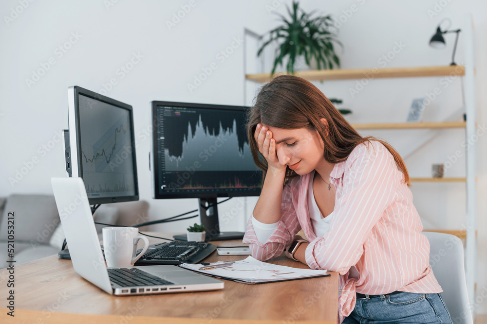 Conception of failure. Female stock broker in casual clothes is working in the office by pc Conception of failure. Female stock broker in casual clothes is working in the office by pc