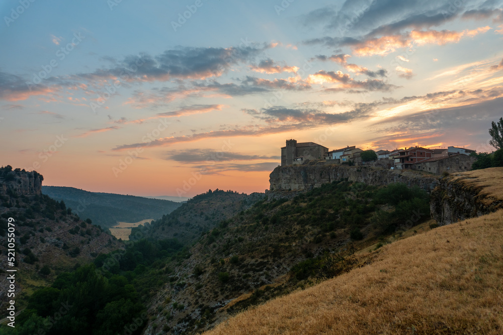 Panoramic view of a sunrise between mountains, with a town on the mountain