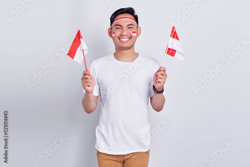 Portrait of Excited young Asian man celebrating indonesian independence day on 17 august and holding indonesian flag isolated on white background studio portrait photo