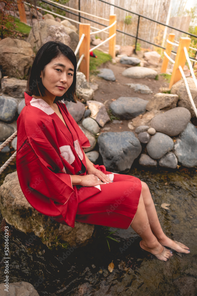 Portrait of sexy and young japanese girl with beautiful old traditional red  kimono sitting on a rock in a water flow in a japanese garden Stock Photo |  Adobe Stock