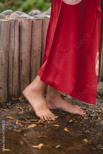 Sexy feet of young japanese girl with beautiful old traditional red kimono stepping on the mud in a japanese garden