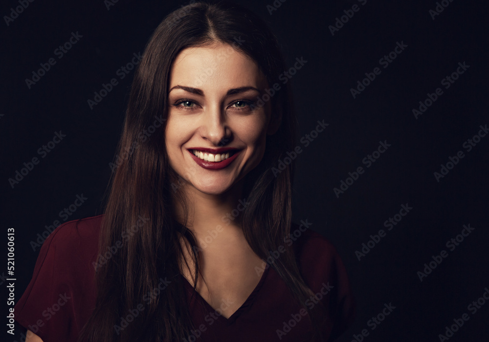 Beautiful young business toothy smiling woman thinking and looking happy in burgundy blouse and with red lipstick on dark shadow black background with empty copy space. Portrait closeup front center Beautiful young business toothy smiling woman thinking and looking happy in burgundy blouse and with red lipstick on dark shadow black background with empty copy space. Portrait closeup front center