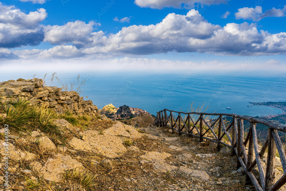 Fototapeta premium mountain landscape with a hiking trail leading to a mountain town and beautiful blue seashore far away