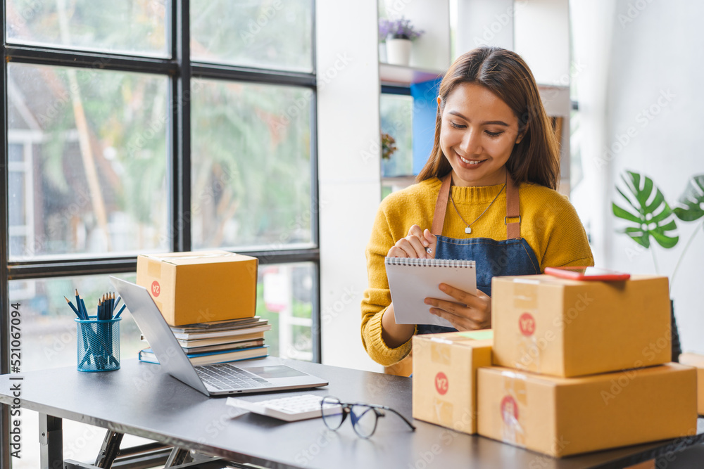 Young excited asian SME woman working with parcel box and preparing product into the box. Young excited asian SME woman working with parcel box and preparing product into the box.