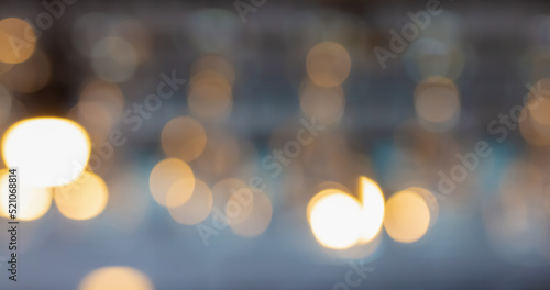Blurred image of glass hanging at a bar drinking a drink. Bright lights in a restaurant. Abstract background.