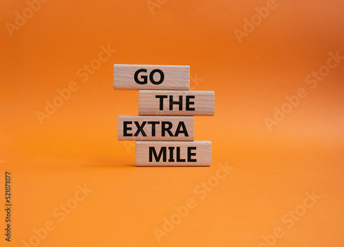 Go the extra mile symbol. Wooden blocks with words Go the extra mile. Beautiful orange background. Business and Go the extra mile concept. Copy space.
