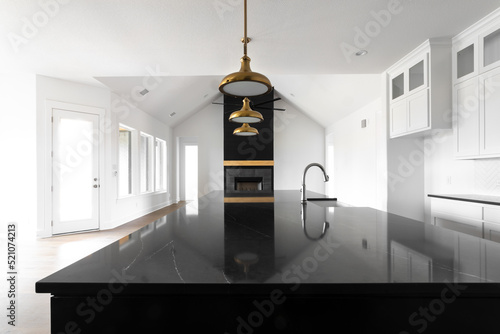 New Construction Modern Home Black Kitchen Island Looking Into Bright Open Living Room with Gold Lights