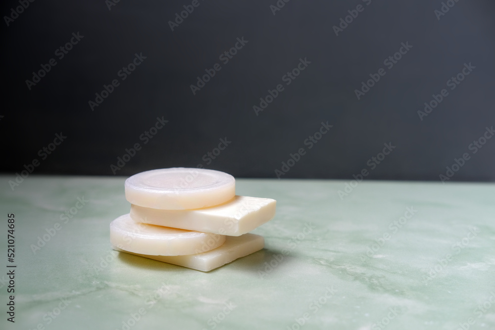 stack of white cleansing soap bars on green stone tile against gray wall stack of white cleansing soap bars on green stone tile against gray wall