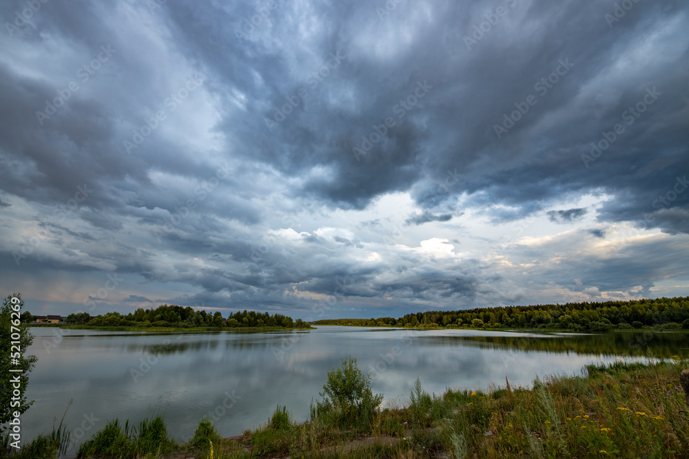 Fototapeta premium landscape with rain clouds. Dramatic sky over the pond.
