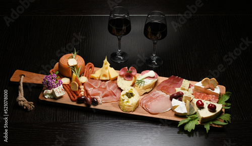 Two red wine glasses with buffet platter with cheese and meats, antipasti, prosciutto, charcuterie.