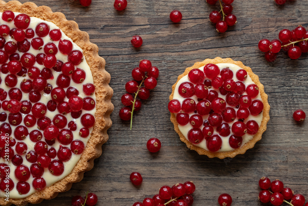 rote Johannisbeeren und Pudding in Törtchen auf Tisch aus Holz Stock ...