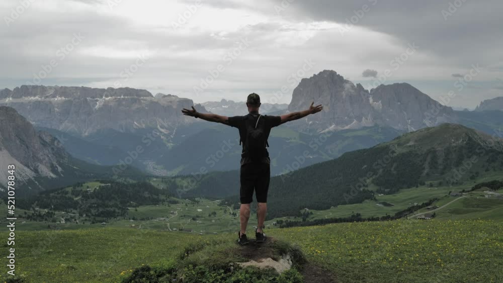 Man standing on top of the rock with arms spread overlooking the mountains Man standing on top of the rock with arms spread overlooking the mountains