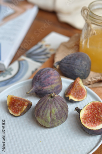 several figs on the table next to a jar of honey on craft paper