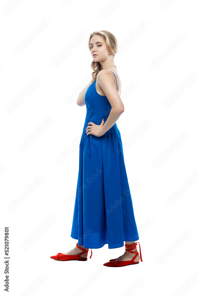 A cute teenage girl in a blue feminine dress and red shoes. Isolated on white background. Vertical.
