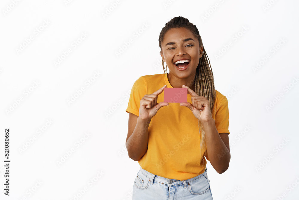 Laughing happy young african american woman, 25s years, showing credit card and smiling, recommending bank, white background Laughing happy young african american woman, 25s years, showing credit card and smiling, recommending bank, white background