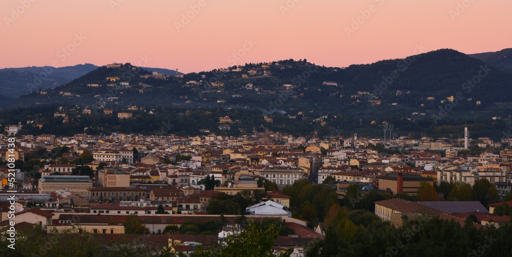 A pink sky dominates over city of Florence during sunset with hills in the background in  Florence, Italy
