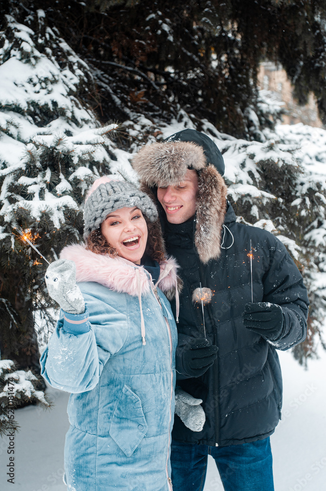 Young beautiful couple in winter forest. Happy couple has fun with snow.