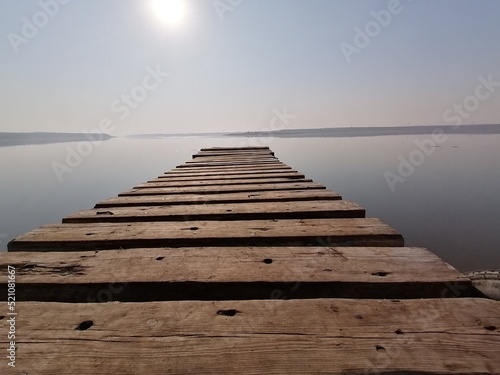 Fototapeta Naklejka Na Ścianę i Meble -  the way forward into the future. A pier on the river bank at sunset