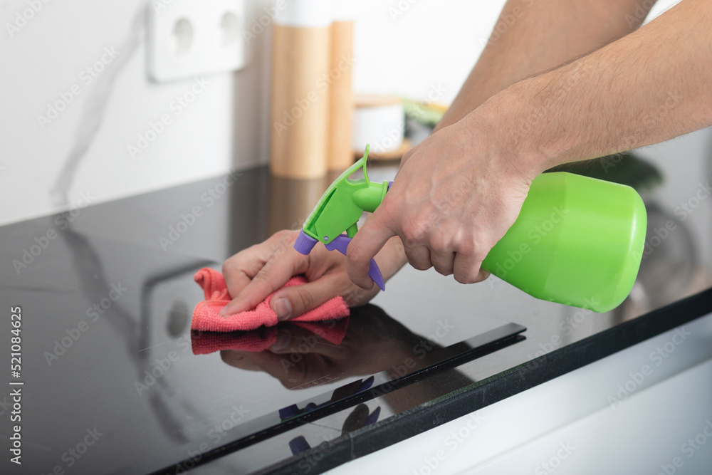 Close up shot of male hands holding bottle spray and cleaning the stove