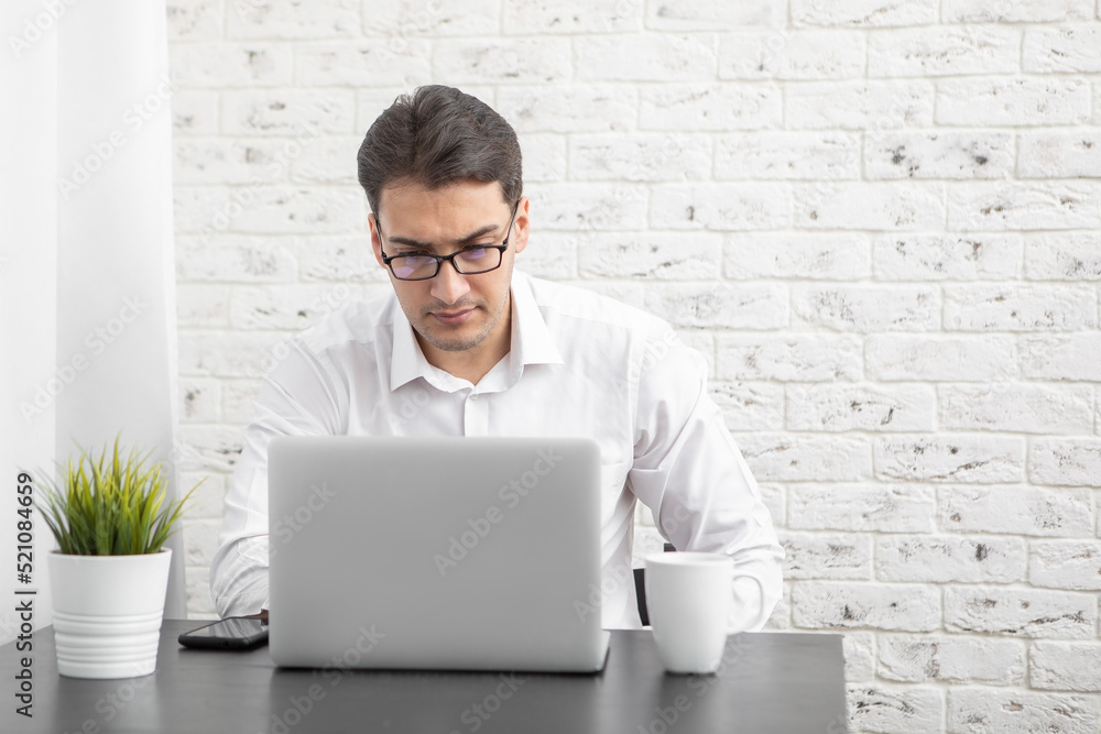 Young businessman working on laptop at home. Distant work concept Young businessman working on laptop at home. Distant work concept
