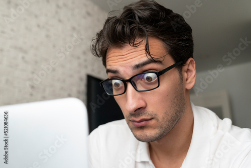 Fototapeta Naklejka Na Ścianę i Meble -  Close up portrait of shocked man with bugged eyes looking at laptop