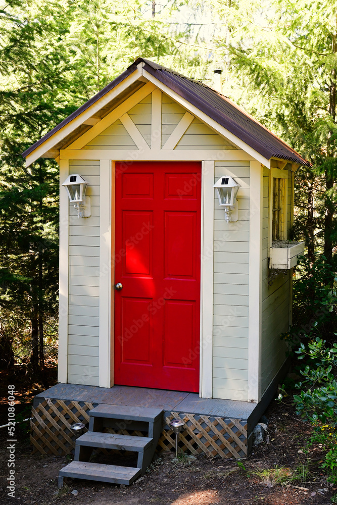 An image of an outdoor composting toilet with bright red door. An image of an outdoor composting toilet with bright red door.
