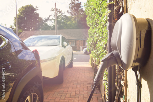 Electric car plugged in to charge outside home with power cable