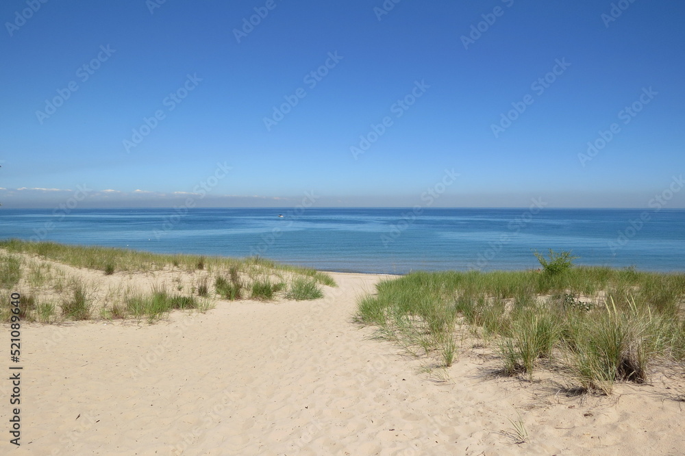 grassy sand dune trail to great lake with sky