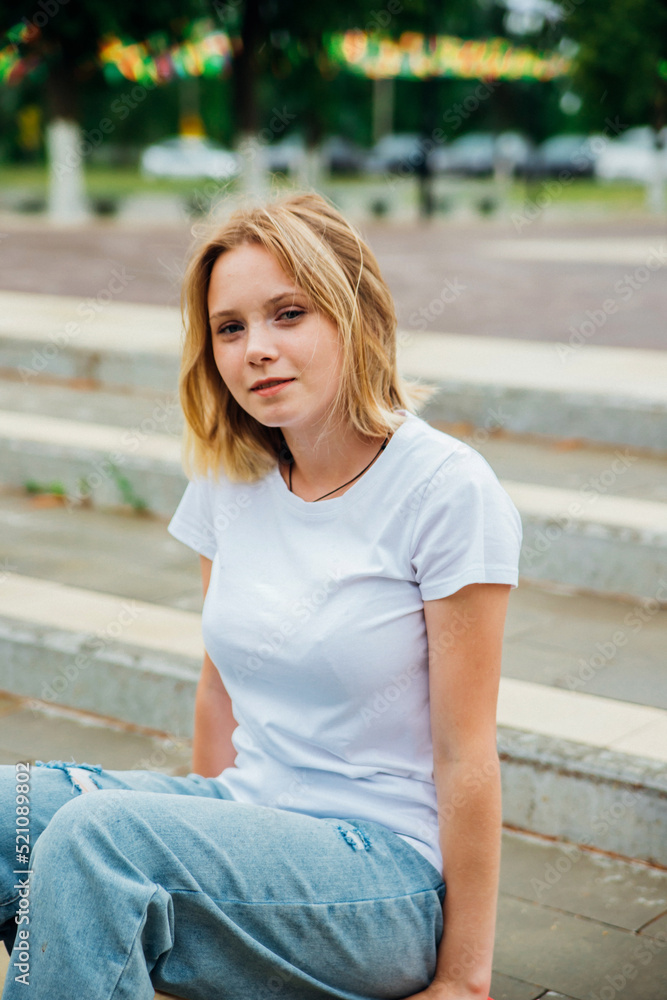 Portrait of a teenage girl in casual clothes in the park. Summer skateboarding, active lifestyle. A student or a schoolboy is sitting on a skateboard during the summer holidays. Sports recreation. Portrait of a teenage girl in casual clothes in the park. Summer skateboarding, active lifestyle. A student or a schoolboy is sitting on a skateboard during the summer holidays. Sports recreation.