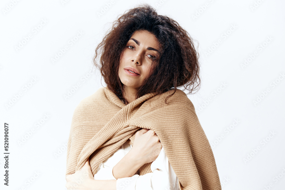 Serious Curly Pretty Latin Woman in Beige Warm Sweater White Shirt Hugging Herself Posing Isolated Looking At Camera At White Studio Wall Background. Fashion Seasonal Sale New Collection Concept Serious Curly Pretty Latin Woman in Beige Warm Sweater White Shirt Hugging Herself Posing Isolated Looking At Camera At White Studio Wall Background. Fashion Seasonal Sale New Collection Concept
