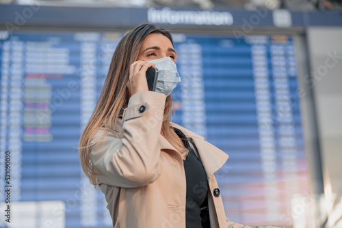 Young lady in mask talking smartphone in the airport