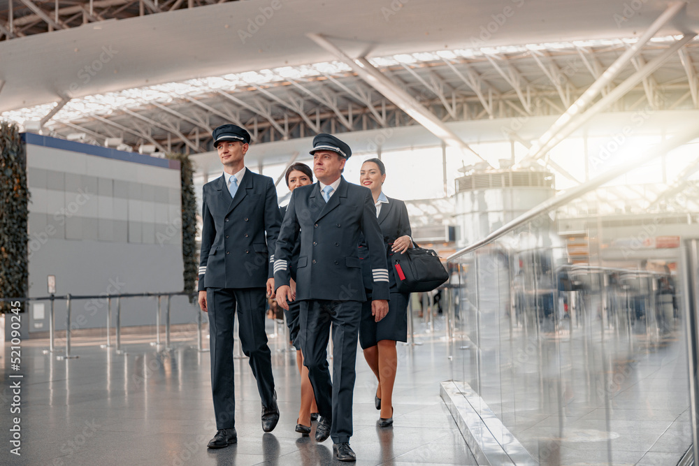 Pilots and stewardesses in uniform walking through the airport terminal