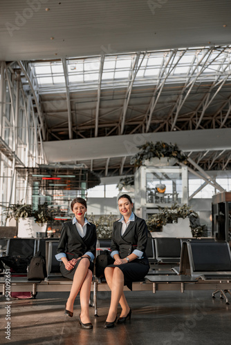 Two flight attendants sitting on the seats in the airport terminal