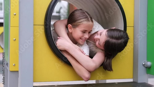 two pretty teen girls playing on a modern playground in identical clothes. sister, bffs. sisterhood, friendship
