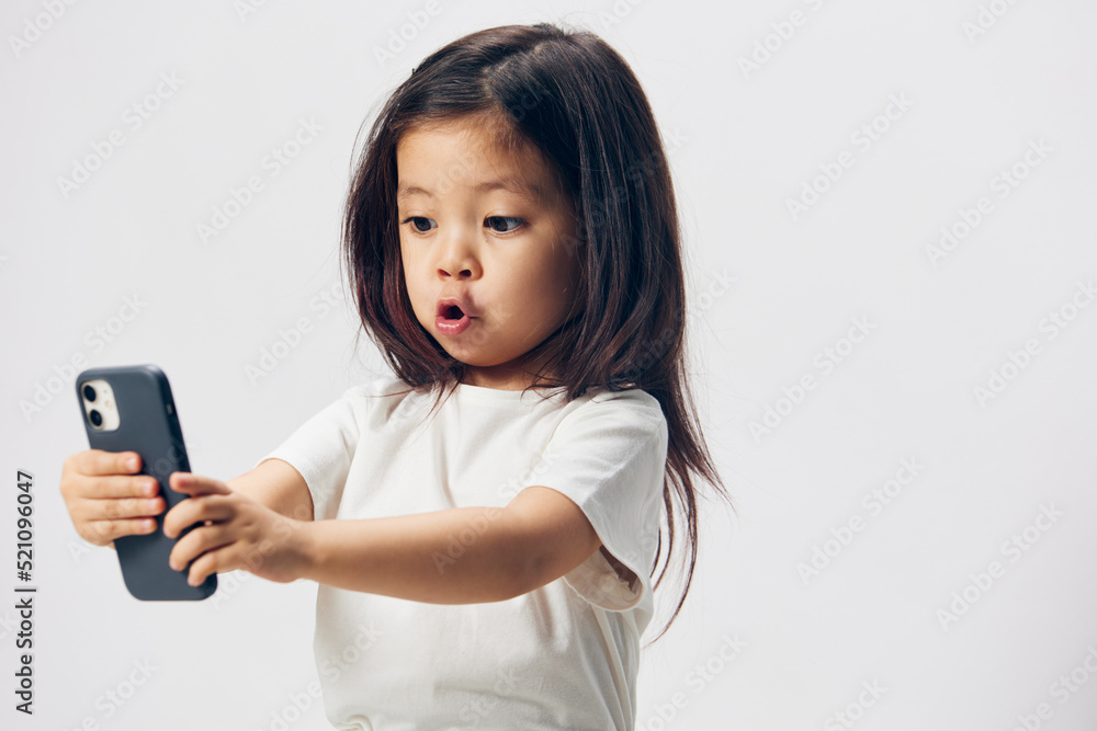funny, cheerful girl makes a funny face while standing with a fashionable smartphone in her hands and taking a selfie. funny, cheerful girl makes a funny face while standing with a fashionable smartphone in her hands and taking a selfie.