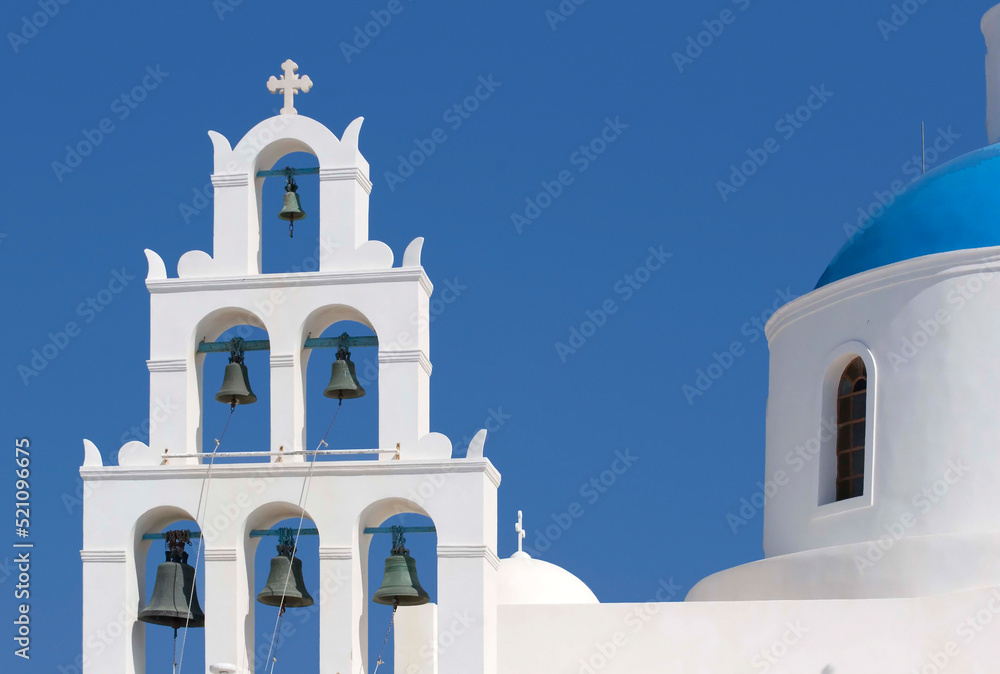 Bell tower and church dome of Church of Panagia Platsani in Oia, in the island Thera - Santorini, Greece, in the summer, against the blue sky 