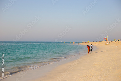 People walk along the beach in Dubai at sunset. Summer walk