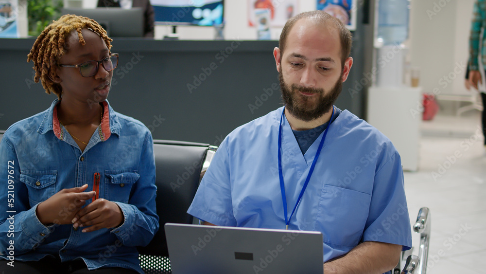 Obraz premium Diverse people analyzing medical diagnosis on laptop in waiting area, woman and male nurse talking about disease and treatment in hospital reception. Specialist consulting patient in clinic lobby.