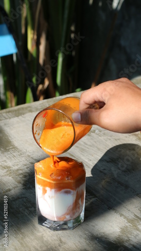 pouring thai tae orange into a glass photo